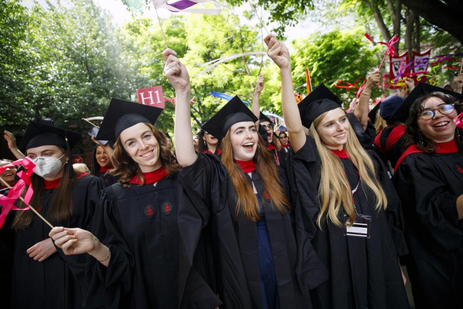 Graduates from Harvard Divinity School celebrate with hand clappers.