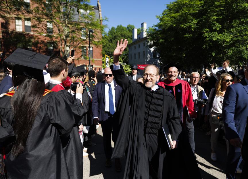 Harvard President Alan Garber waves to attendees as he passes Widener Library.