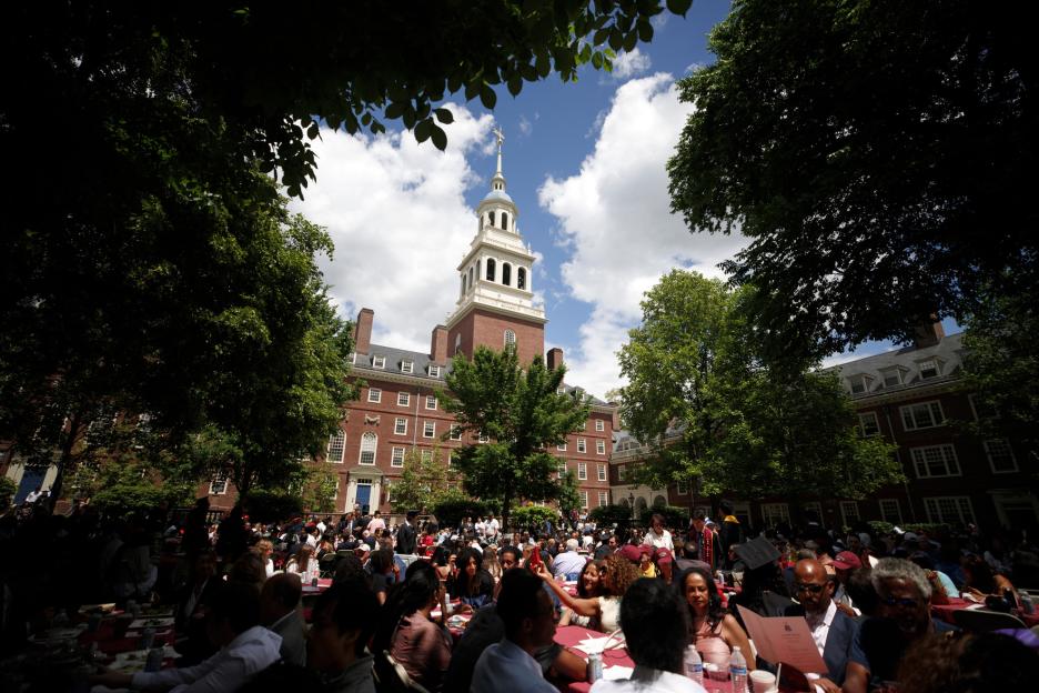 The tower of Lowell House rises above family and friends gathered in the courtyard for House Ceremonies.