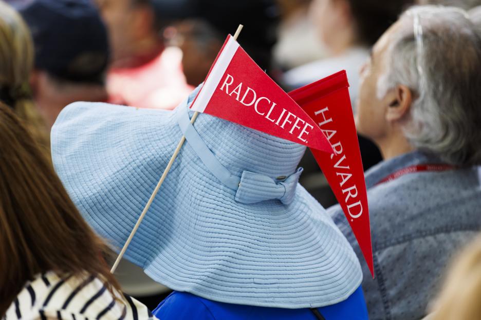 A Harvard Alumni Day attendee sports Radcliffe and Harvard pennants on their hat.