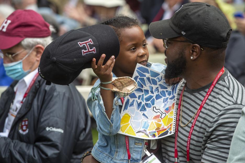 Nyla Dockery, 7, removes her Harvard hat while having a quiet conversation with her dad Prince Dockery '03, back for his 20th reunion on Harvard Alumni Day, 2022.