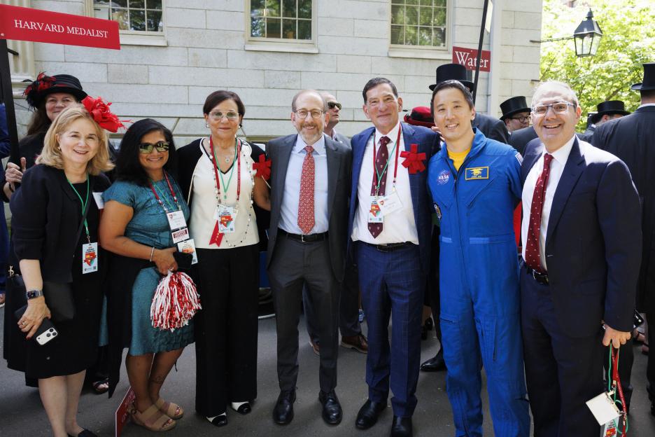 Cynthia A. Torres AB ’80, MBA ’84 (from left); Moitri Chowdhury Savard AB ’93; Penny Pritzker, Senior Fellow of the Harvard Corporation; Alan Garber, President of Harvard University; Will Makris EdM ’00, President of the Harvard Alumni Association; Jonny Kim MD ’16, Harvard Alumni Day Speaker; and David Battat AB ’91, Incoming HAA President; pose for a photo during the parade on Harvard Alumni Day 2026