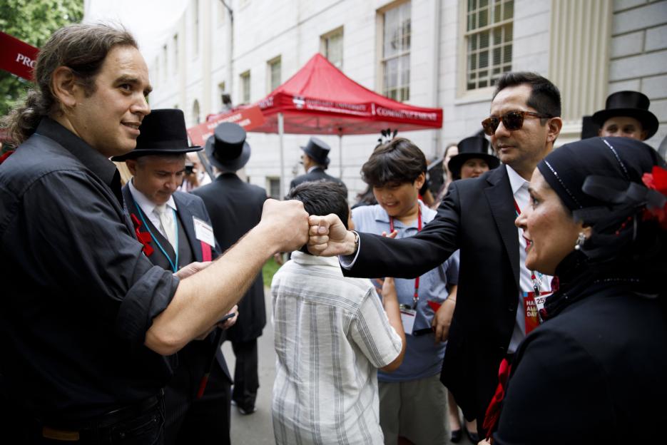 Justin Krebs '00 bumps fists with classmate Christopher Amar as they assemble for a parade in Old Yard during Harvard Alumni Day, 2025.
